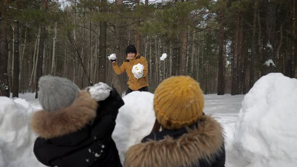 Man Is Playing Snowballs with His Family, Wife and Little Son Hiding Before Snow Wall.