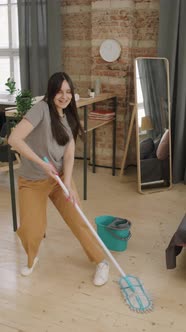 Vertical Shot of Young Woman Dancing and Mopping