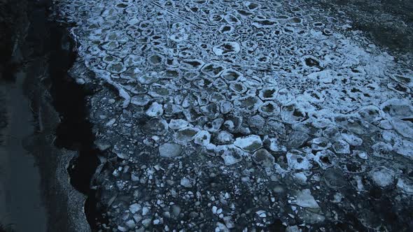 Panning Up Scenic Sunset Ice Drifting with Fallen Trees During Windy Weather with Waves at Aerial