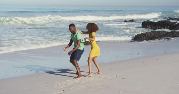 African American man carrying his wife on his back seaside