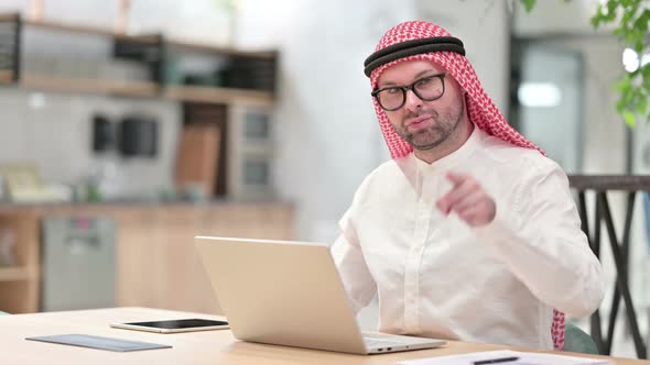 Young Arab Businessman with Laptop Pointing at the Camera 