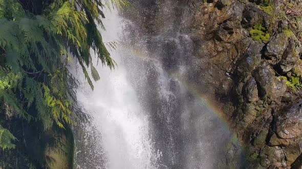 A tiny rainbow forms in the cool mist of a clean magical waterfall in a national park