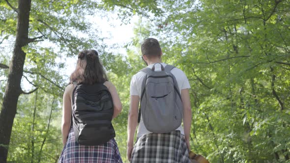 Portrait of Guy and Young Girlfriend Walking in the Forest. Pair of Travelers with Backpacks