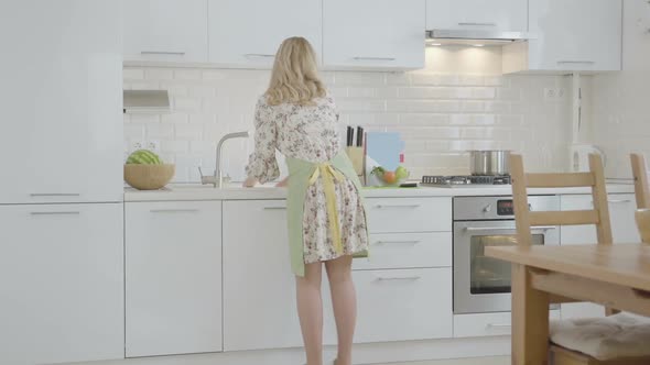 Backside View Woman Cuts Vegetables and Flowing Water