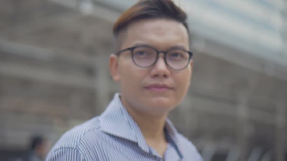 Asian businessman smiling and looking at camera standing on the urban city.