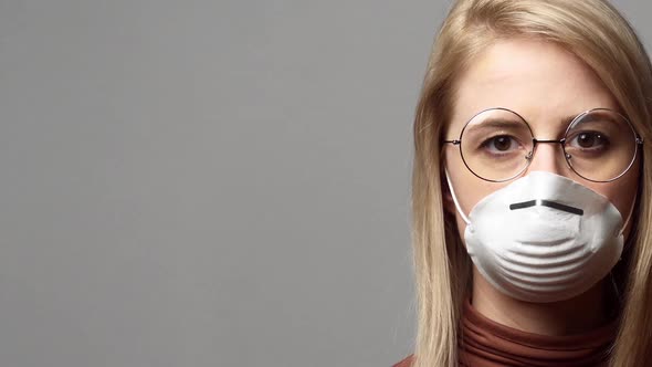 Blonde woman in protective mask on grey background