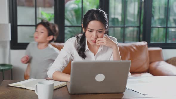 Asian business woman mother loss concentration on job in computer because the kids making noise.