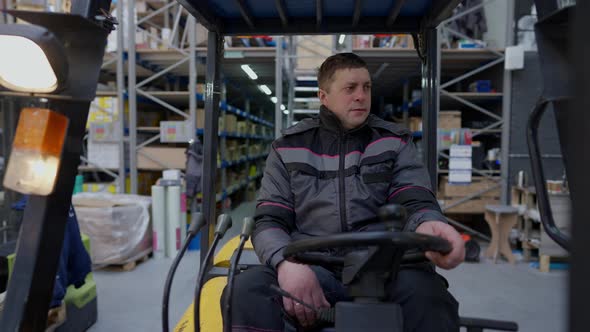 Front View Forklift Operator Driving in Large Industrial Warehouse Indoors