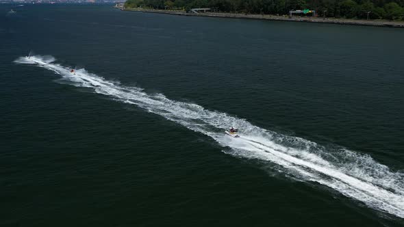 Chasing jet skis under the Verrazano Bridge from a left profile to center  as they enjoy the waves o