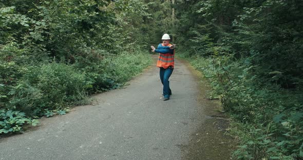 Worker in Workwear Signals with Gesture That Passage on Forest Road is Blocked