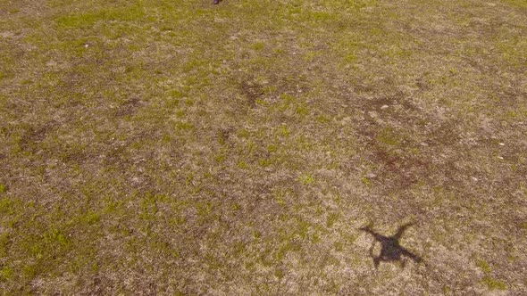 Landing drone on a dry grass field and tilting the camera to see the pilot at the end.