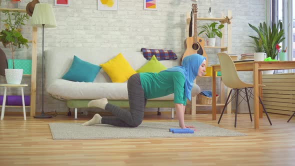 Sporty Muslim Woman in Hijab Doing Exercises in a Modern Apartment
