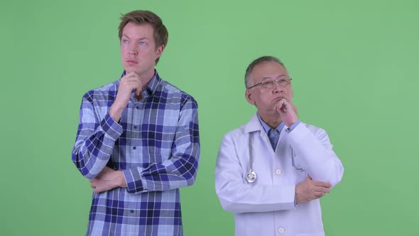 Happy Mature Japanese Man Doctor with Young Man Thinking Together