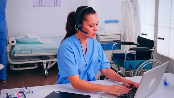 Receptionist Operator Speaking Online with Patients Using Headphone