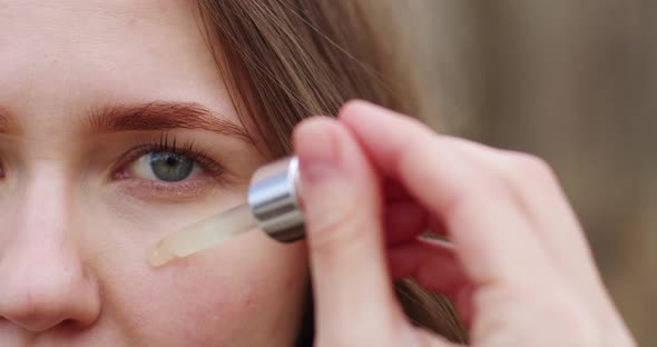 close-up of the girl's face, half of the face in the frame, skin care, applying serum with a glass p