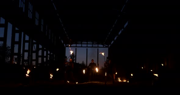 A Group of Professional Artists with Fire Show the Show Juggling and Dancing with Fire in Slow