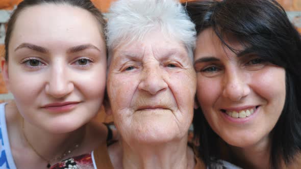 Portrait of Elderly Woman with Her Daughter and Granddaughter Looking Into Camera Together