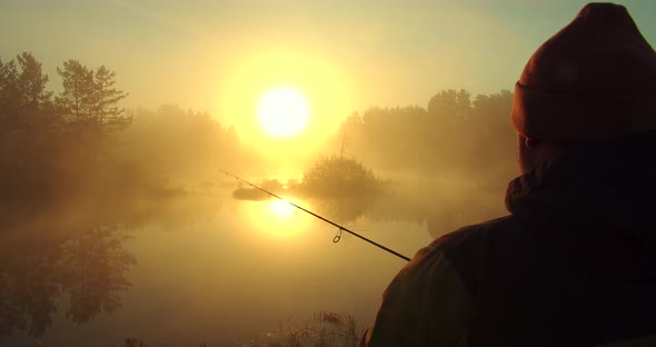 Unrecognizable Man Fishing in Lake at Dawn