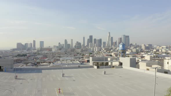 AERIAL: Guy Sitting on Parking Deck with Downtown Los Angeles, California Skyline in Background