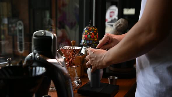 The barista is making coffee in a drip method for customers.