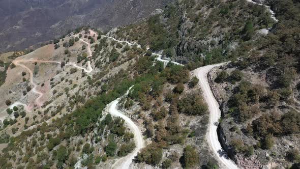 Hairpin roads in arid mountain landscape of Copper Canyon, Mexico, forward tilt up aerial