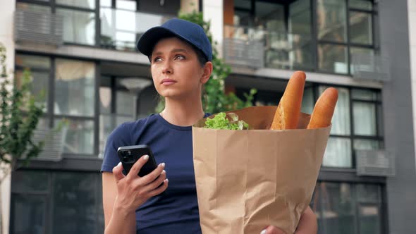 Food Delivery Woman Courier Uses Smartphone Holds Paper Bag Looking Address