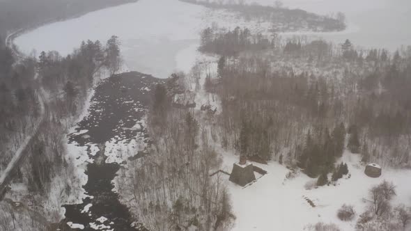 Aerial above Katahdin Ironworks during Winter snowfall TILTING ORBITING SHOT