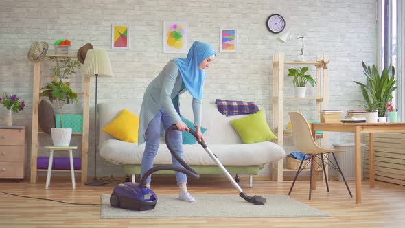 Muslim Woman in Hijab Doing House Cleaning with a Vacuum Cleaner