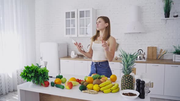 Pretty woman holds tablet in the kitchen.