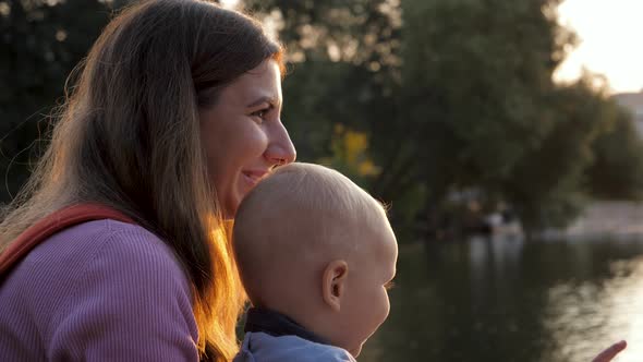 Happy Caucasian Mother And Her Child Watch Sunset On Summer Evening In Park