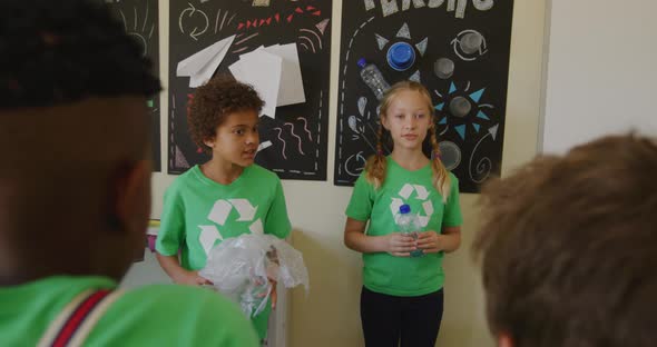 Two girls wearing recycle symbol tshirt holding plastic bottle and bag