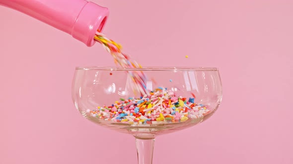 Colorful Candy Confectionery Run Poured Into a Wineglass Glass on Pink Background