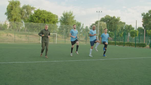 Soccer Players Performing High Knee Running Exercise Outdoors at Dawn