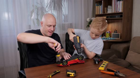 Father Teaching Son How to Repair a Toy Car with a Screwdriver