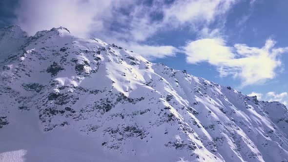 Aerial drone shot of epic sunlight breaking over the white snowy alps and mountains above the vacati