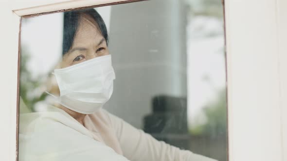 Lonely Asian old woman looking outside the window, Stay home for quarantine.