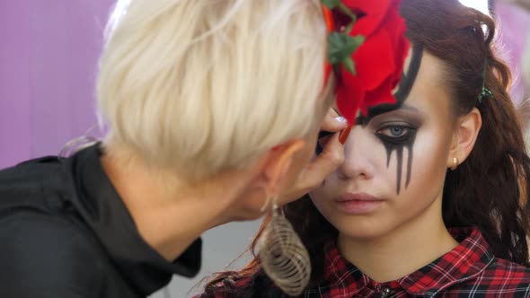 Easy Halloween Makeup. Girl in a Beauty Salon. Applying a Stylistic Pattern on the Face of the Model