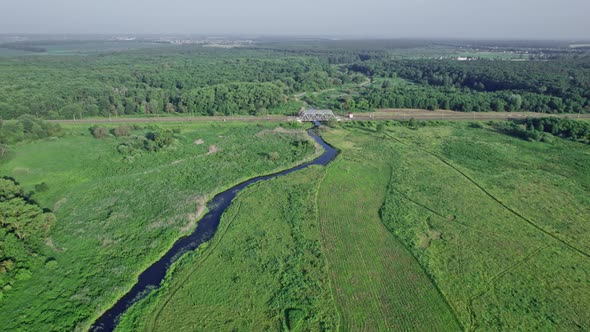 Railway Bridge Among Green Meadows Over a Small River in the Countryside