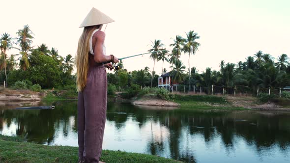 Close up shot of traditional asian girl with Asian conical hat fishing in tropical lake in Asia - Or