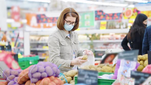 Woman in Mask Putting Potatoes in Bag at Store
