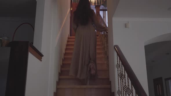 Back View of Eerie Woman Walking Up the Stairs Slowly and Entering Room in House. Brunette Barefoot