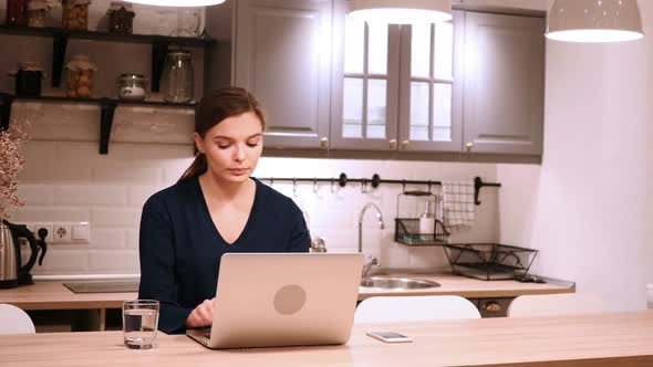 Woman Working on Laptop Upset By Loss Sitting in Kitchen