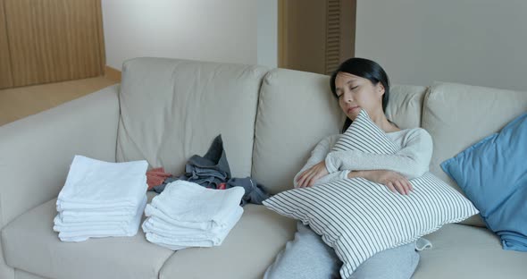 Woman fold towel and sit on sofa