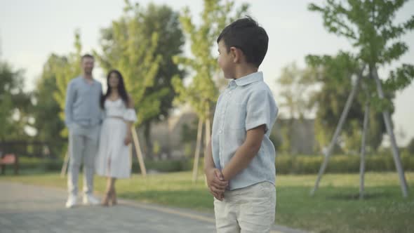 Charming Cheerful Little Boy Looking Back Couple Blurred Parents Smiling Camera