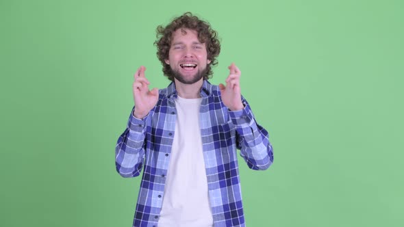 Happy Young Bearded Hipster Man Wishing with Fingers Crossed