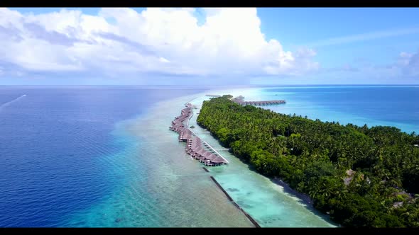 Aerial flying over landscape of tranquil island beach vacation by blue water and bright sand backgro