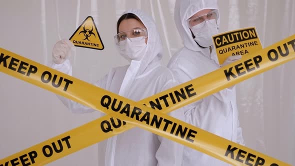 Two Doctors in Protective Suits in the Lab with Placards CAUTION QUARANTINE AREA