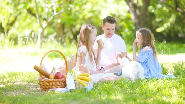 Happy Father and Little Daughers Relax By the Lake