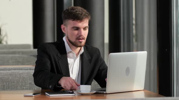 Businessman Working at His Laptop in a Small Cafe