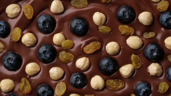 Chocolate with hazelnuts, blueberry, raisin top view, rotate